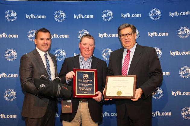  Shane Wells, President of Butler County Farm Bureau (center), accepts the award from John Sparrow, Chief Executive Officer of KFB Insurance Companies (left), and David S. Beck, Executive Vice President of the KFB Federation (right), during a December 1 recognition and awards program.  