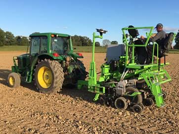Technicians plant 4 row plots for the Kentucky Corn Variety Trial.  The technician riding the planter is changing corn hybrids on the go by dumping a small amount of seeds as the planter moves down the field.  The tractor is operating on auto-steer to insure even spacing between planter passes.