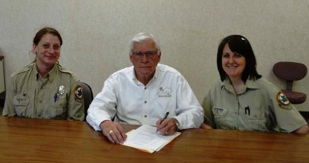 Forest ranger Susan Nightingale (left) and forester Chris Oelschlager (right) are present as Judge Executive David Fields signs an Arbor Day Proclamation.