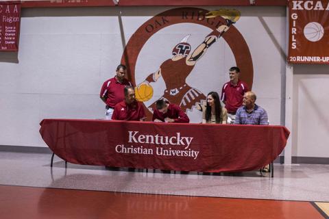 Coach Joey Kirby and Assistant Coach Adam Kirby look on as Cory Mason signs.  Joining Cory at the table are KCU Coach Grady Lowe and his parents Lori and Glen Mason.