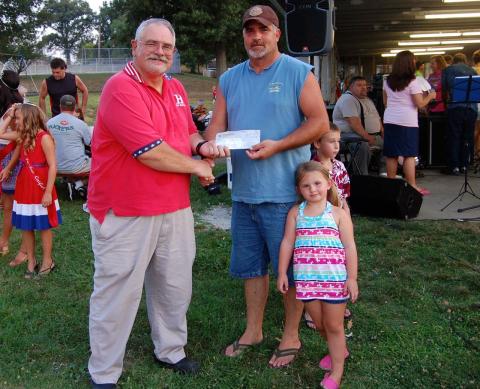 David Hocker of Hocker Family Insurance presents Todd McDaniel with a $250 check for catching the largest catfish during the fishing tournament.