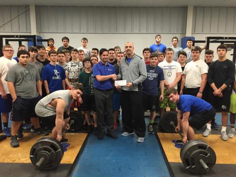 MBT employee Andrew Guilaran presents a check to Coach Bivens and the football team.