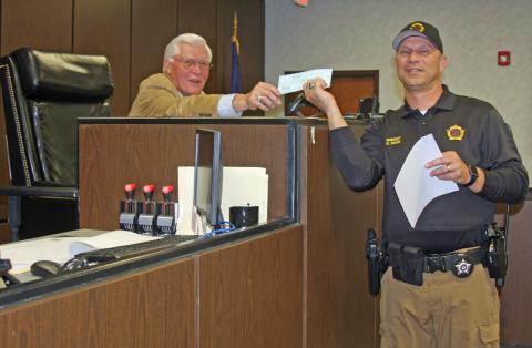 Butler County Sheriff Scottie Ward presents excess fees to Judge David Fields.