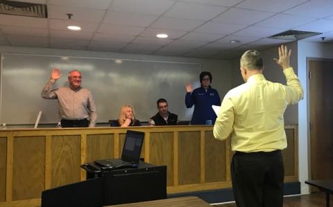 Assistant Superintendent Robert Tuck administering oath of office to Delbert Johnson and Aimee Sanders.