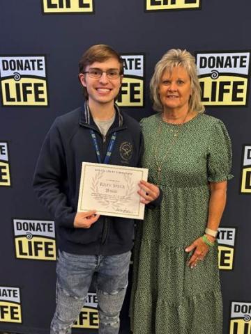 Riley Speck today: UK Public Policy Student, receiving 2026 Donate Life KY Scholarship by Circuit Clerk’s Association President & Montgomery County Circuit Clerk, Tanya Terry, in May 2026: