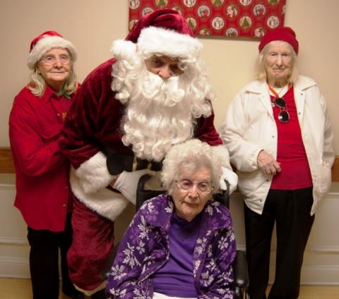 Nancy Keown, seated, and sisters Ona Mitchell and Bulah Skipper-Middleton catch Santa's ear.