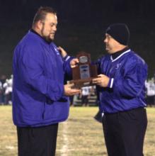 Coach Ryan Emmick is presented the District Runner-Up trophy from  Supt. Scott Howard