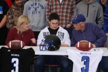 Drake Embry signs his letter of intent with parents Sheri Anderson and Richard Embry looking on.