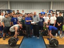 MBT employee Andrew Guilaran presents a check to Coach Bivens and the football team.   