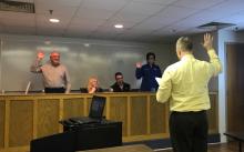 Assistant Superintendent Robert Tuck administering oath of office to Delbert Johnson and Aimee Sanders.
