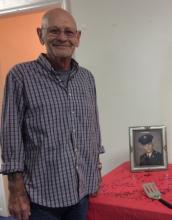 Larry Jones poses in front of his service picture during Saturday's Quilts of Valor ceremony.  "Looks just like me," Jones laughed.  